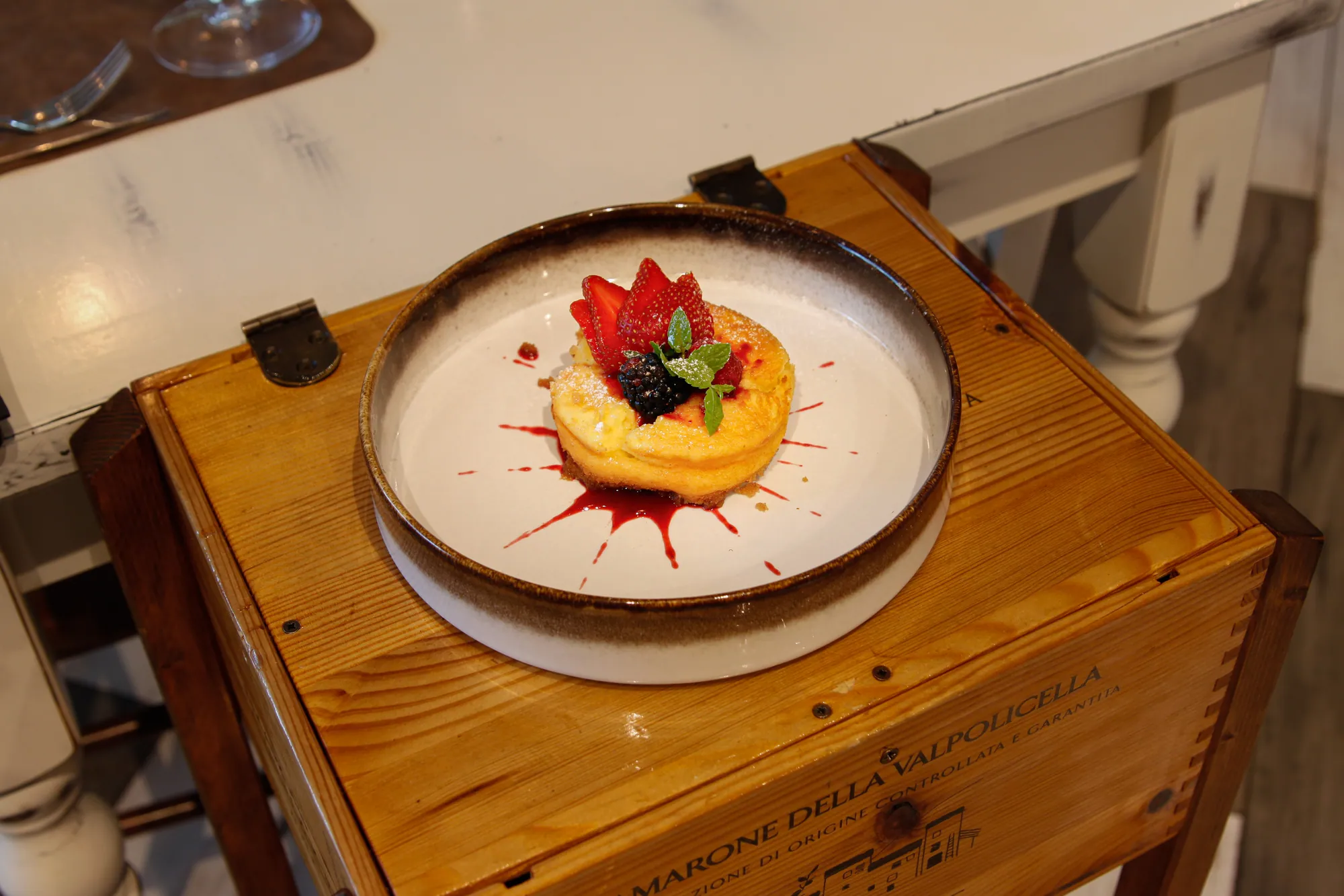 Cheesecake con frutti rossi e coulis, servita su piatto di ceramica