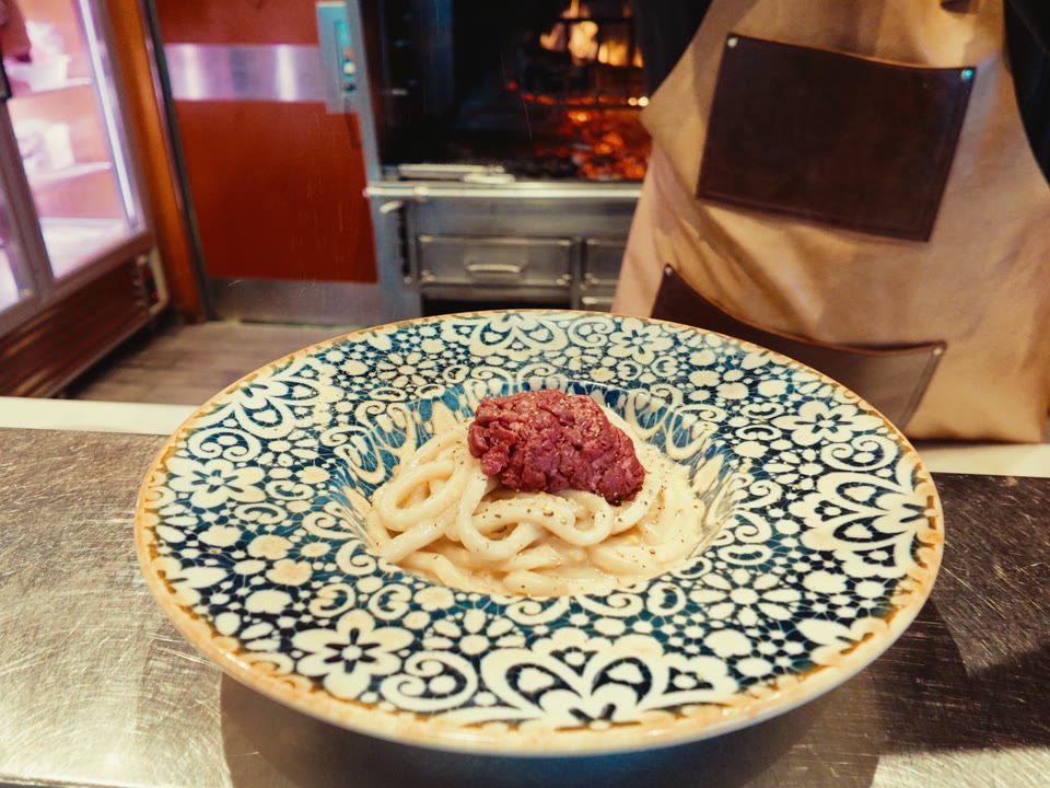 Pici cacio e pepe con tartare di Chianina, serviti davanti alla brace